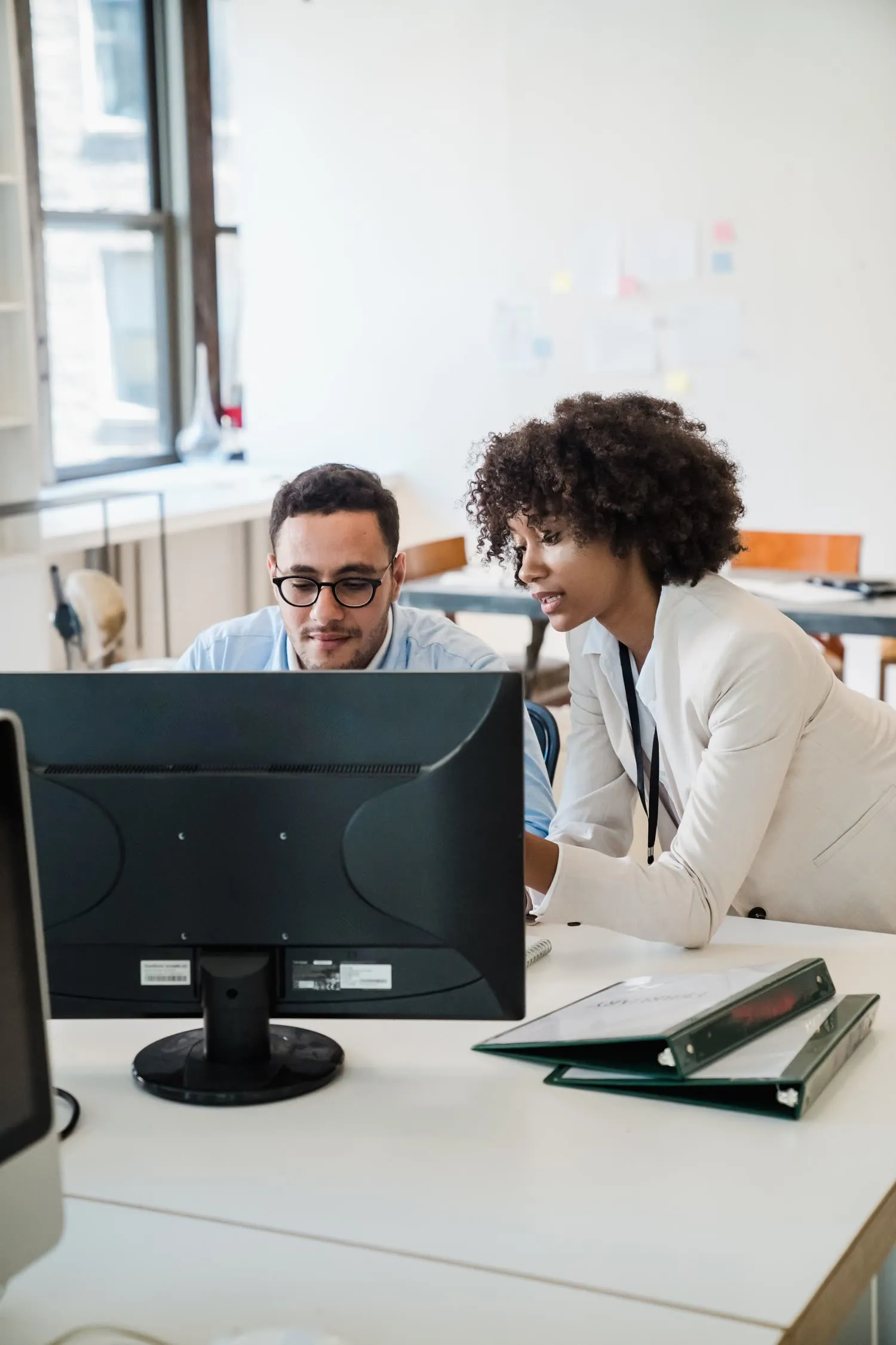 Two colleagues reviewing work together at a screen