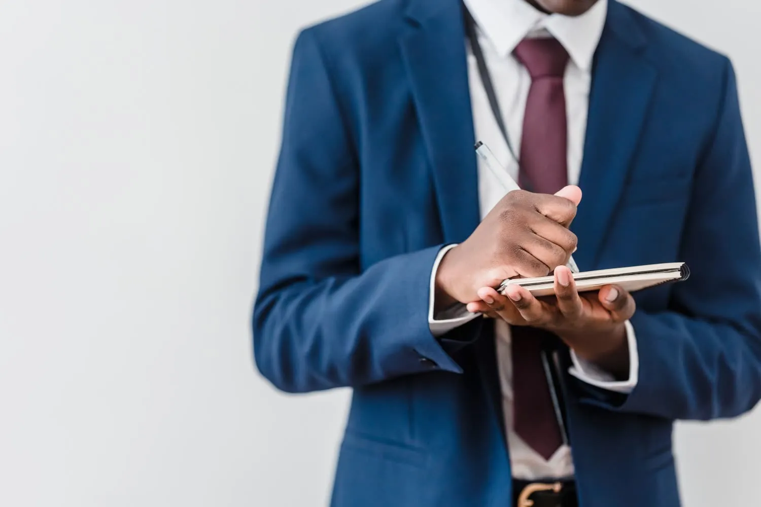 A professional in a navy suit taking notes in a notebook
