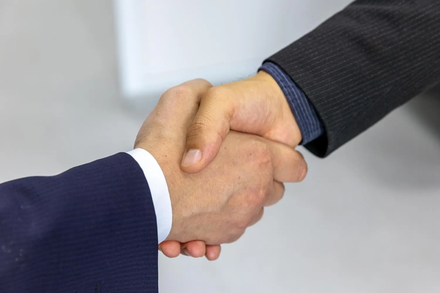 Two people in business attire shaking hands after an agreement